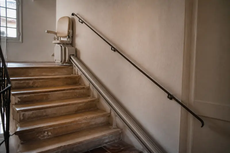 Escalier en pierre d'un immeuble ancien équipé d'un siège monte-escalier