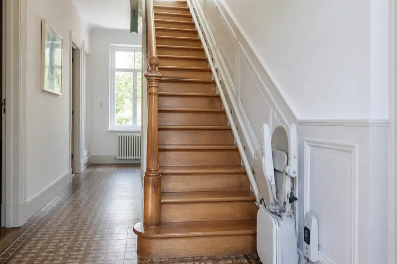 Escalier droit d'un pavillon avec un siège monte-escalier posé sur le rail